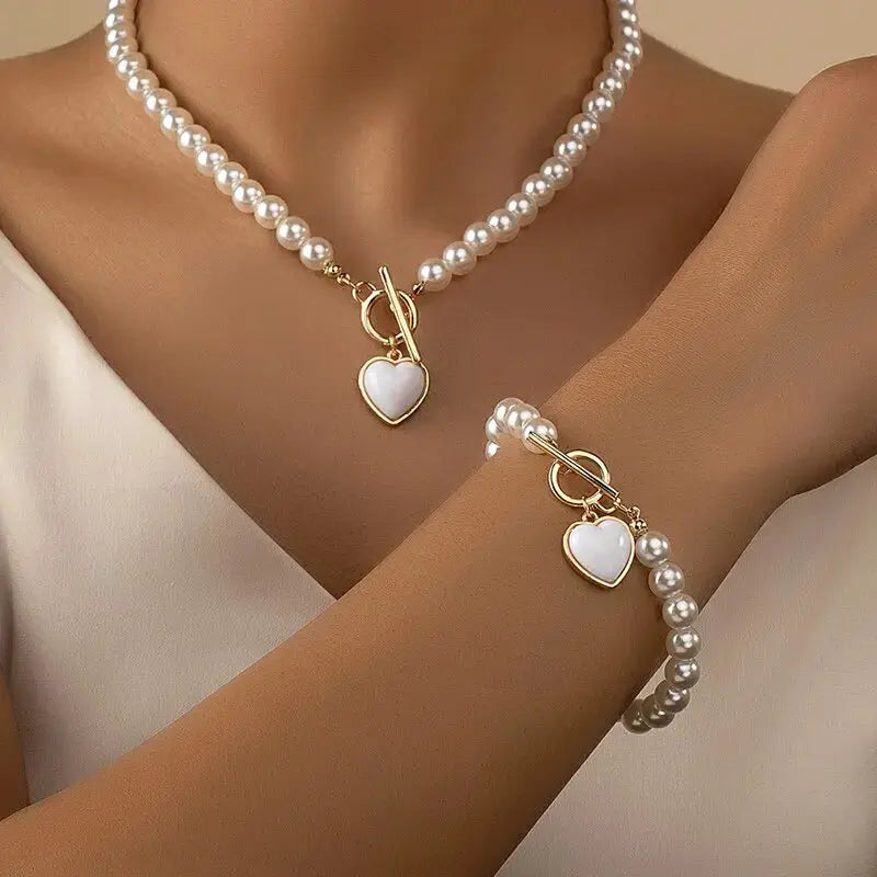 Pearl necklace and bracelet set for women; 2-piece white imitation pearl jewelry with gold heart pendants.