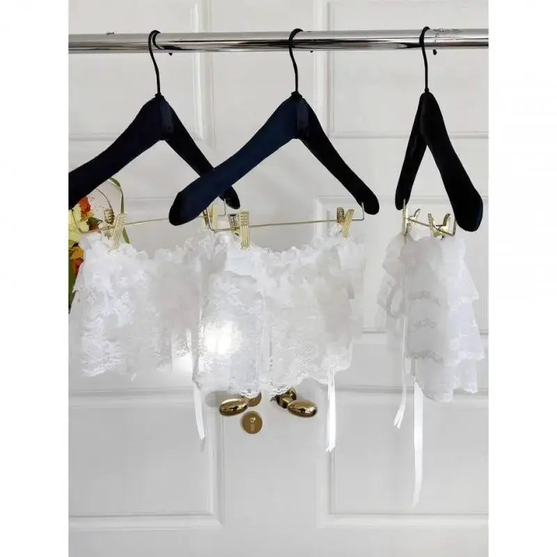 Three white lace layered mini skirts with lace trim on black hangers