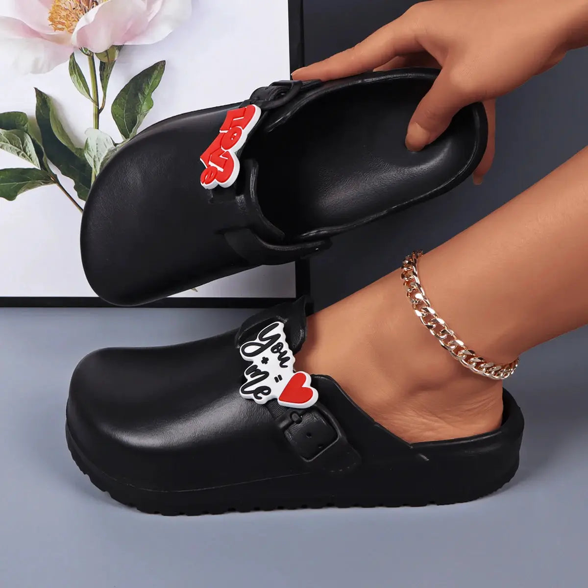 Black EVA slides with buckle straps and charm tags; waterproof indoor/outdoor footwear for women (2 shown)