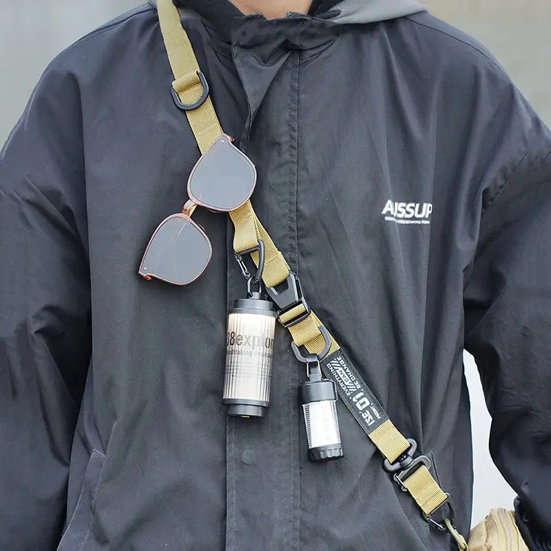 Outdoor crossbody strap by Simples Market; tan adjustable tactical bag strap with metal clips and two sunglasses attached