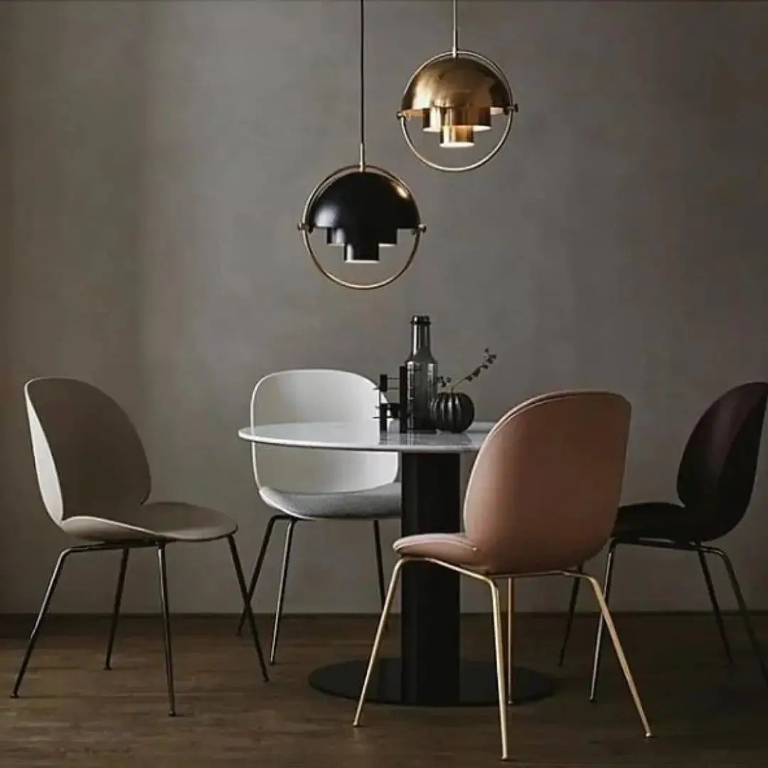 Pendant lights: twin spherical iron shades in gold and black with circular ring frames above a dining table.