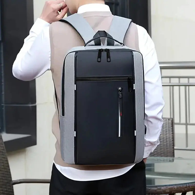 Neutral-style backpack in gray with a black front panel; suitable for men and women, for business, travel, and school use.