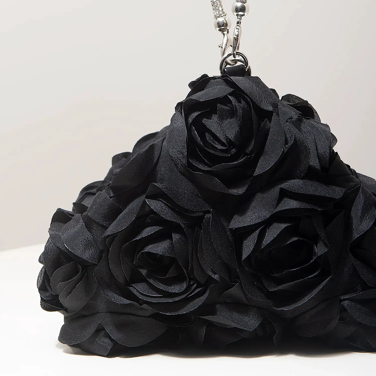 Mini purse with black fabric rose-petal design and a silver chain strap.