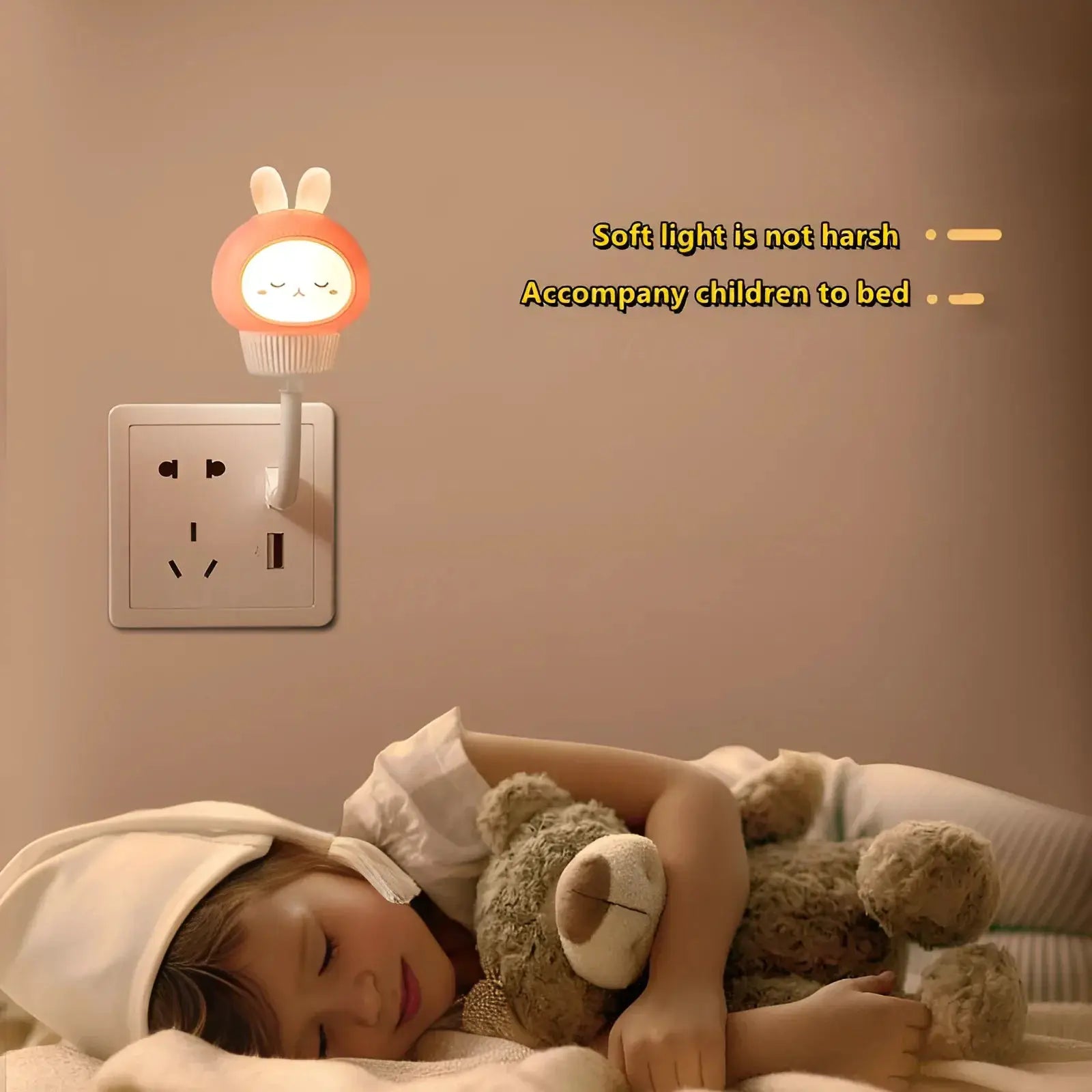 USB night light LED cartoon lamp with pink bunny hood, plugged into wall outlet beside sleeping child and teddy bear