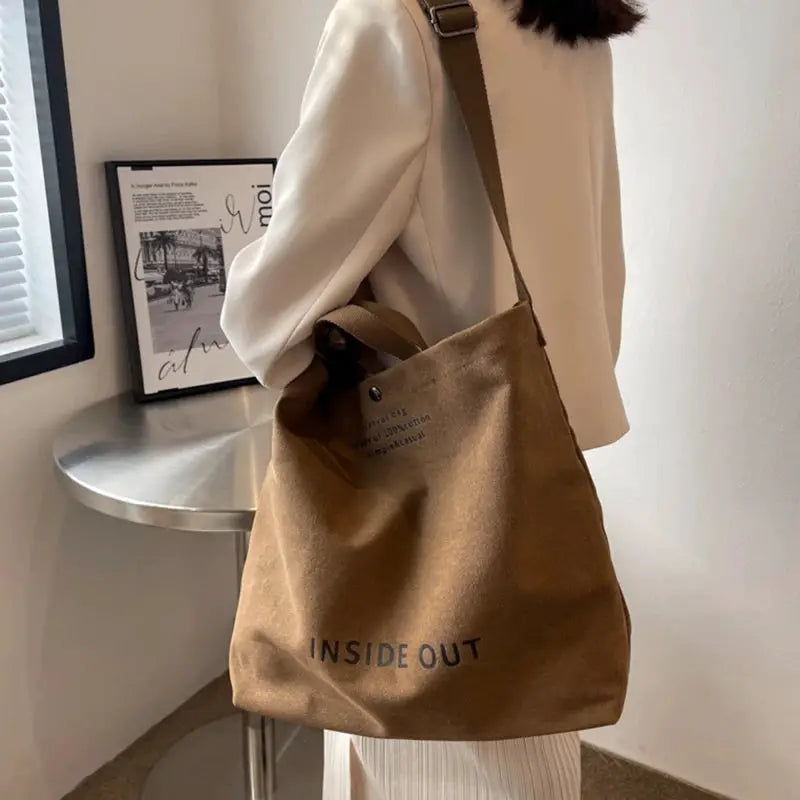 Brown canvas cross-body bag with tan strap, large-capacity tote for everyday use.