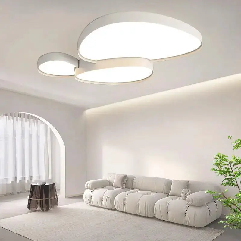 Modern white LED ceiling lamp with three circular panels and remote control in a bright living room.