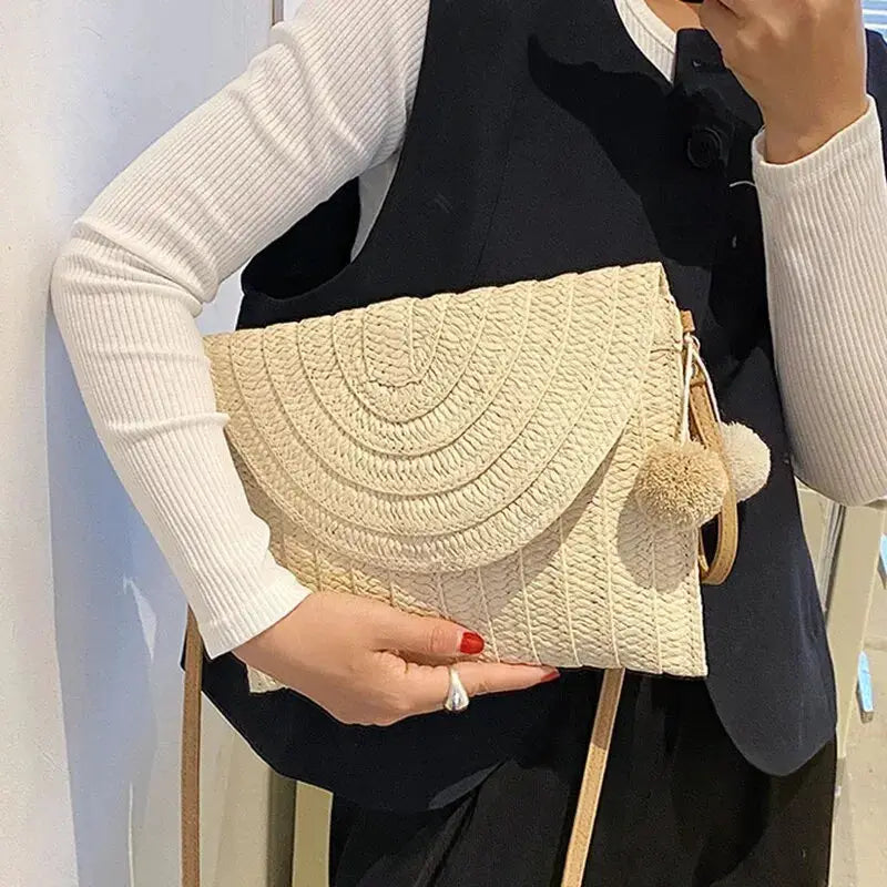 Handmade straw crossbody bag with envelope flap, natural beige woven design and two pom-pom tassels