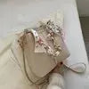 Beige bucket shoulder bag with chain and ribbon detail, crossbody style