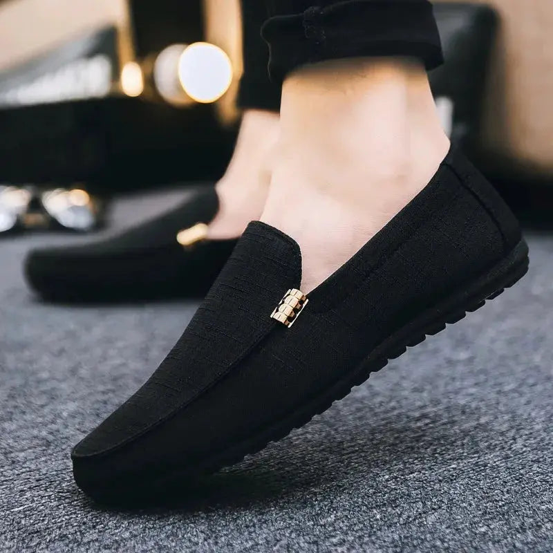 Pair of men's black canvas slip-on loafers with gold accent, casual dress shoes.