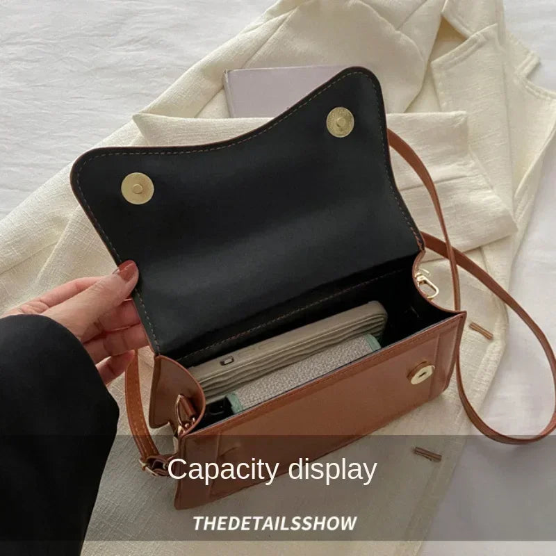 PU leather handbag with brown exterior, black interior, magnetic snap flap and crossbody strap