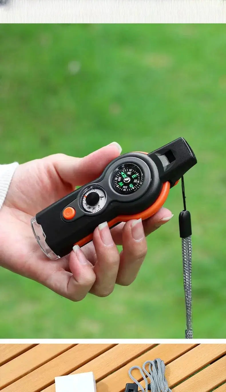 7-in-1 outdoor survival whistle by Simples Market with compass, black body and orange accents, lanyard