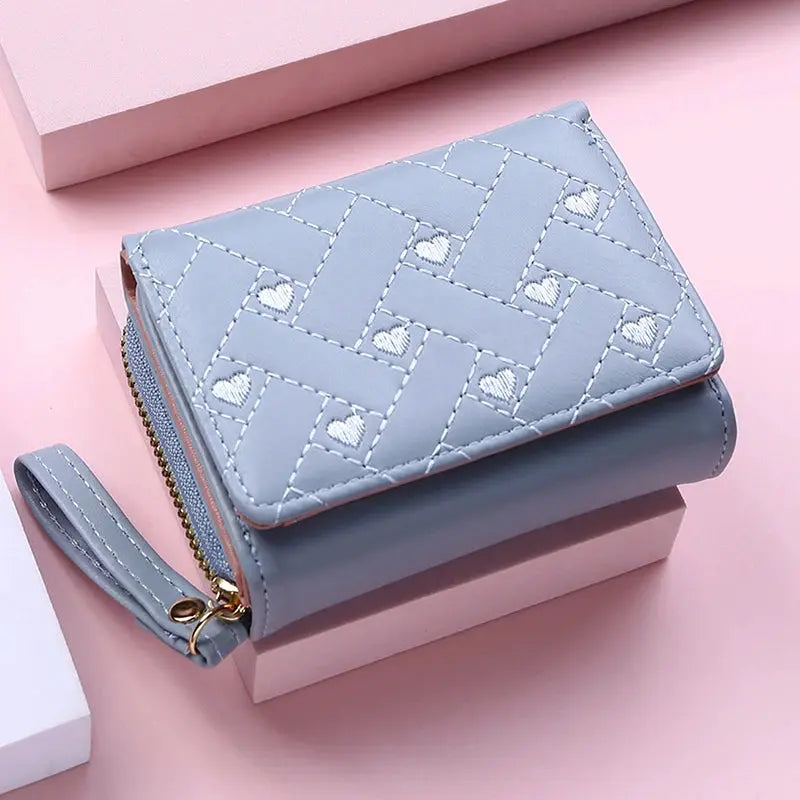 Women's wallet in light-blue PU with quilted pattern and heart embroidery, zip-around closure, wrist strap.
