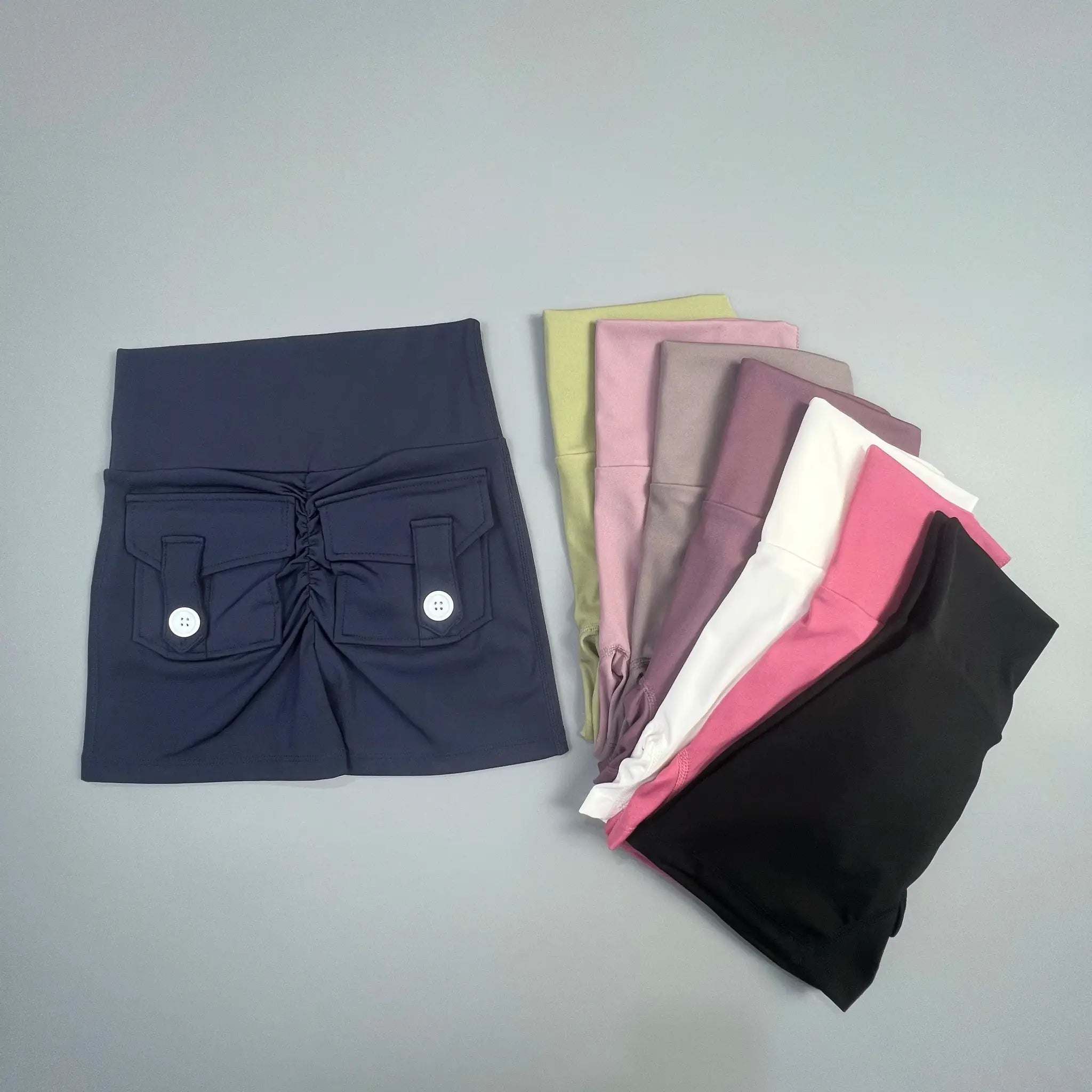 Simples Market navy cargo fitness shorts with front patch pockets and button details; pastel shorts stacked beside