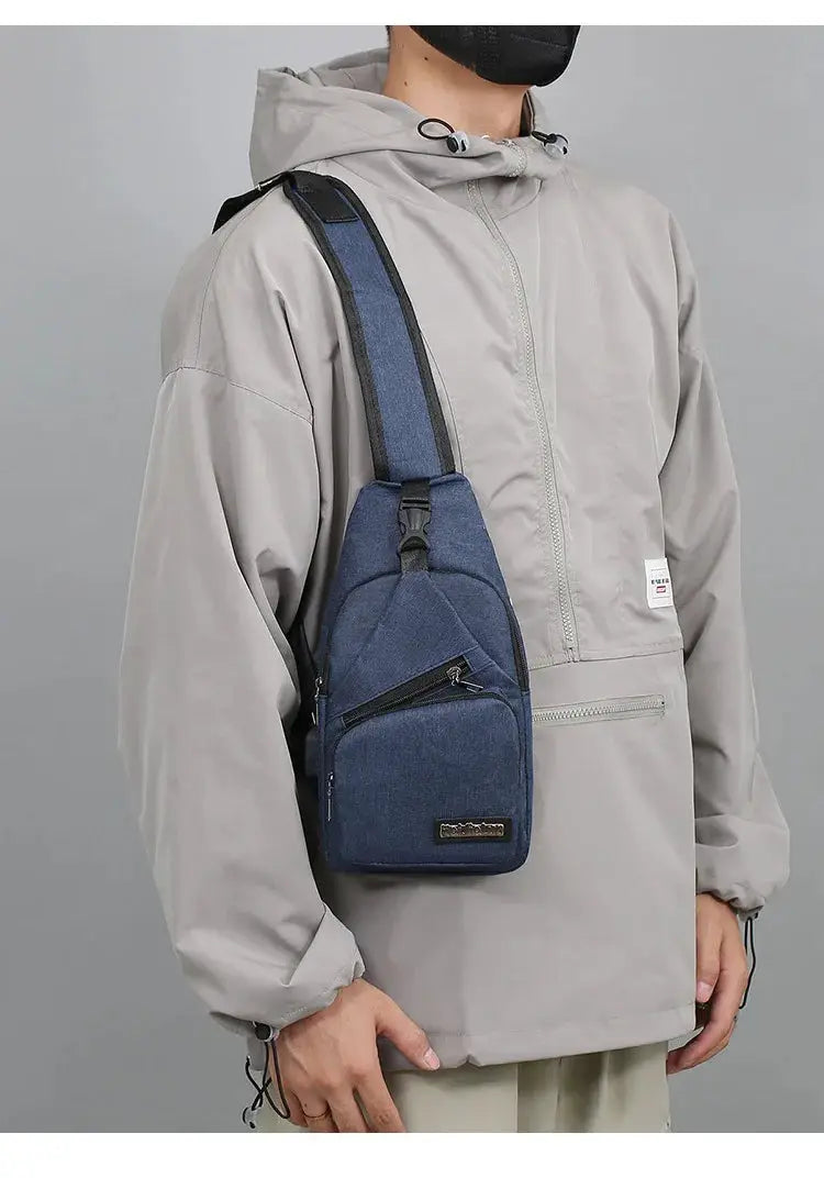 Simples Market men's chest bag in navy blue canvas worn crossbody over a light gray jacket