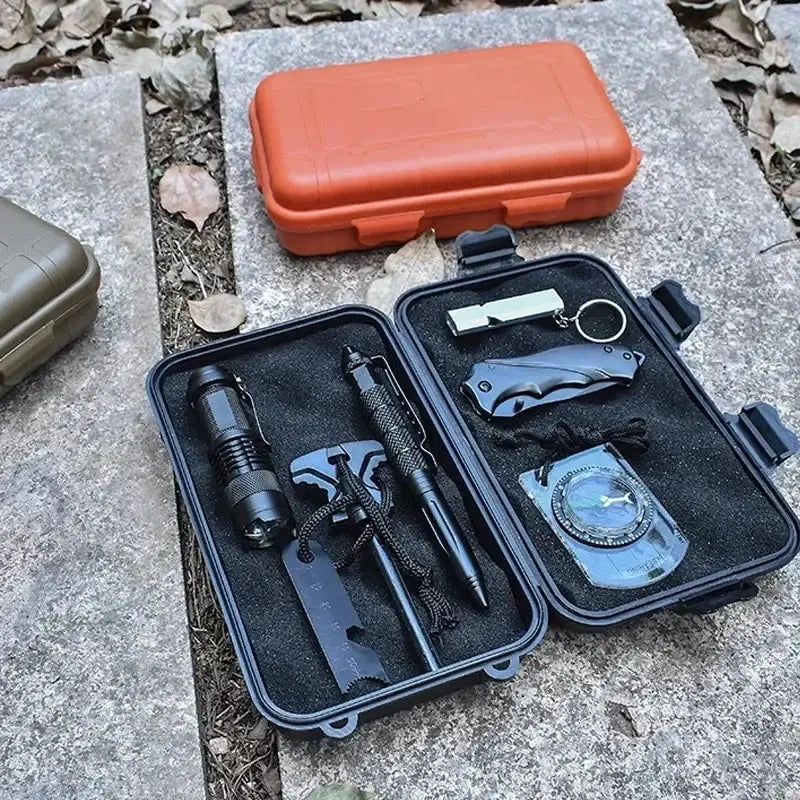 Outdoor survival box set by Simples Market; two black waterproof cases open with flashlight, knife, compass, and multitool.