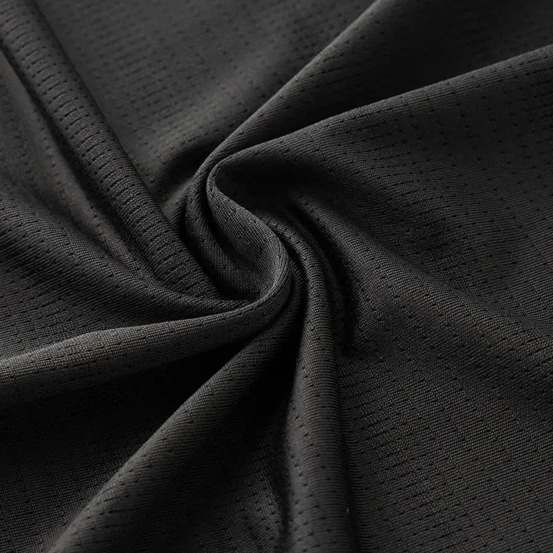 Running T-shirt fabric close-up in black with breathable perforated mesh pattern.