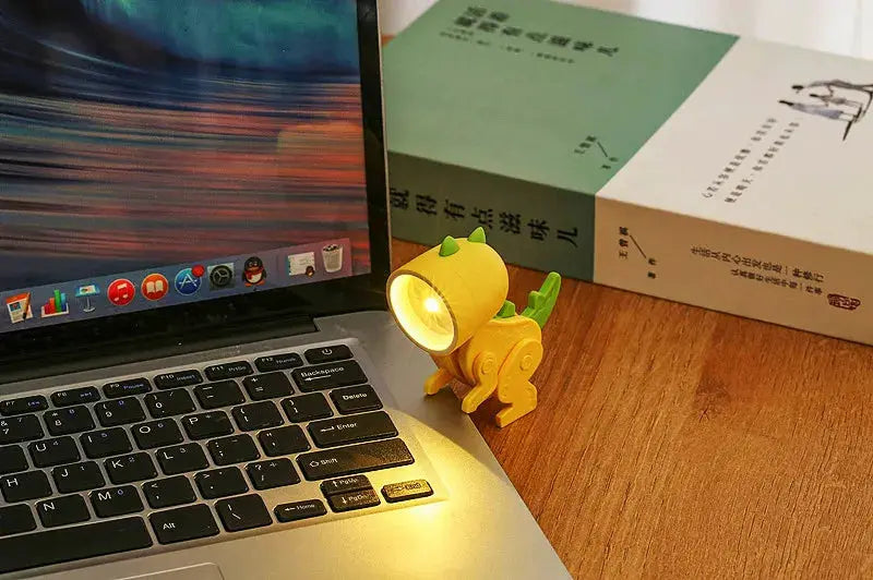 Mini night light LED cartoon hero police desk lamp, yellow plastic, on a wooden desk beside a laptop