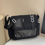 Black ita bag with clear front pocket and zip, adjustable crossbody strap, and white ring accents.