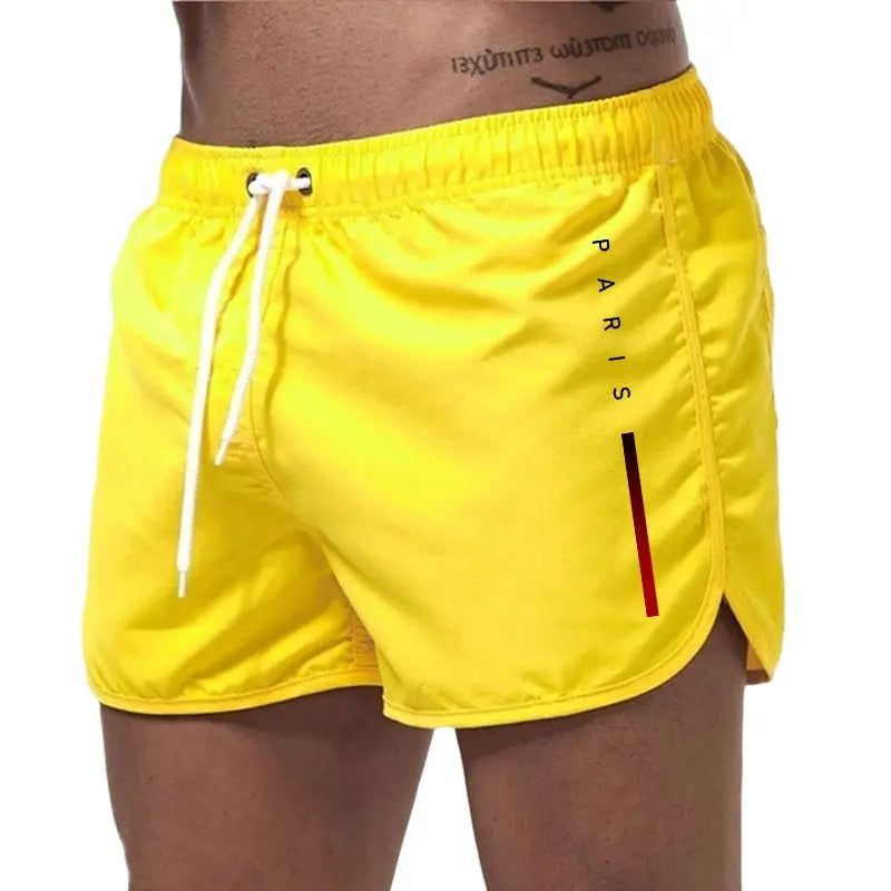 Men's bright yellow board shorts with white drawstring, side Paris print and curved hem