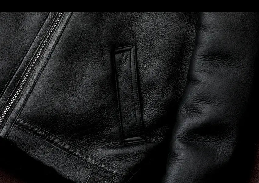 Black leather jacket with metal front zipper and vertical welt pocket; close-up leather texture.