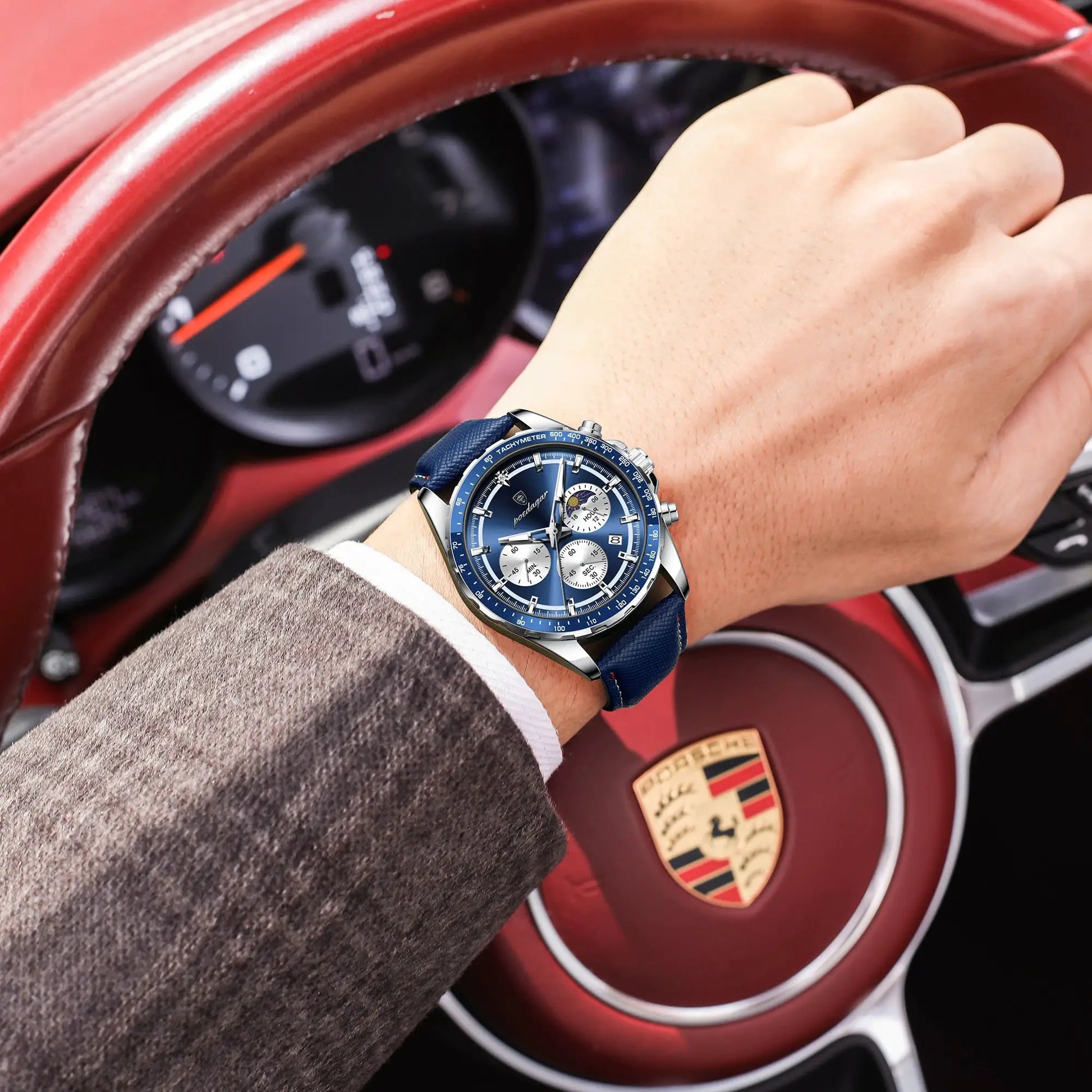 POEDAGAR men's blue chronograph wristwatch with leather strap on wrist in Porsche car interior.