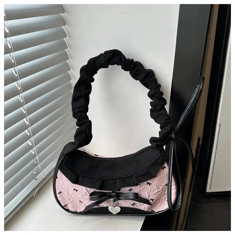 Hand-held pink quilted bag with black velvet scrunchie handle and bow charm