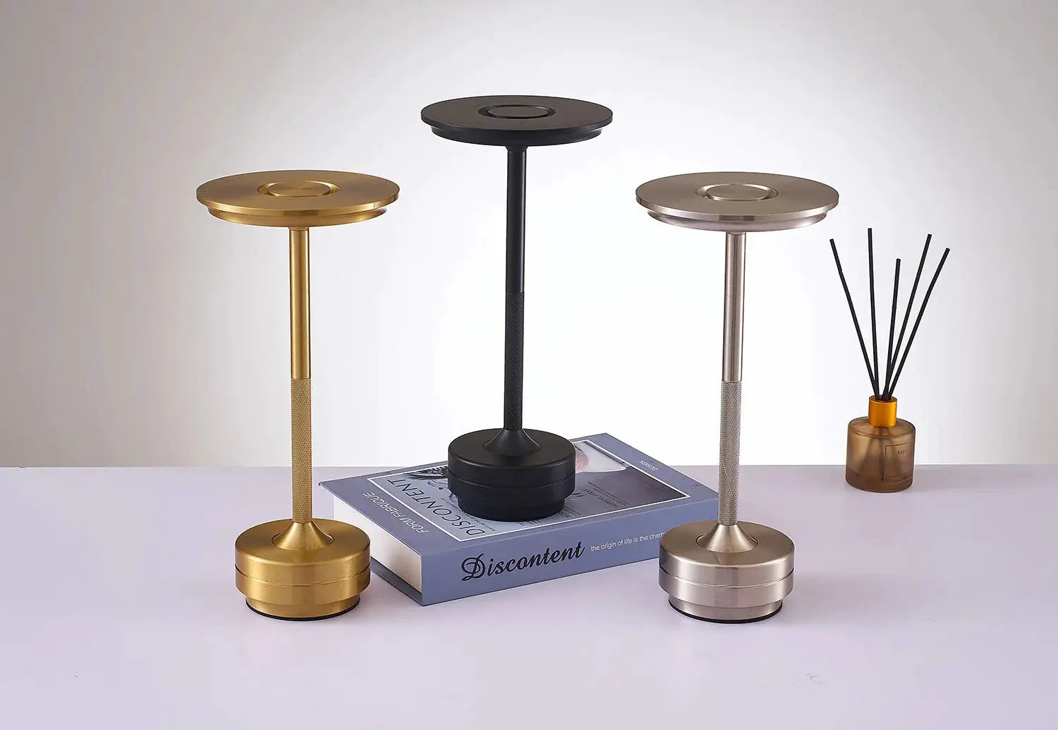 Simples Market wireless infinitely dimmable table lamps set of 3 in gold, black, and silver with round tops.