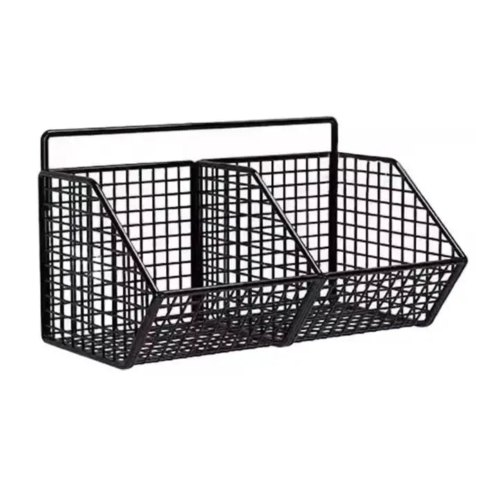 Wall-mounted black metal wire kitchen storage basket with three compartments for spices, garlic, and onions.
