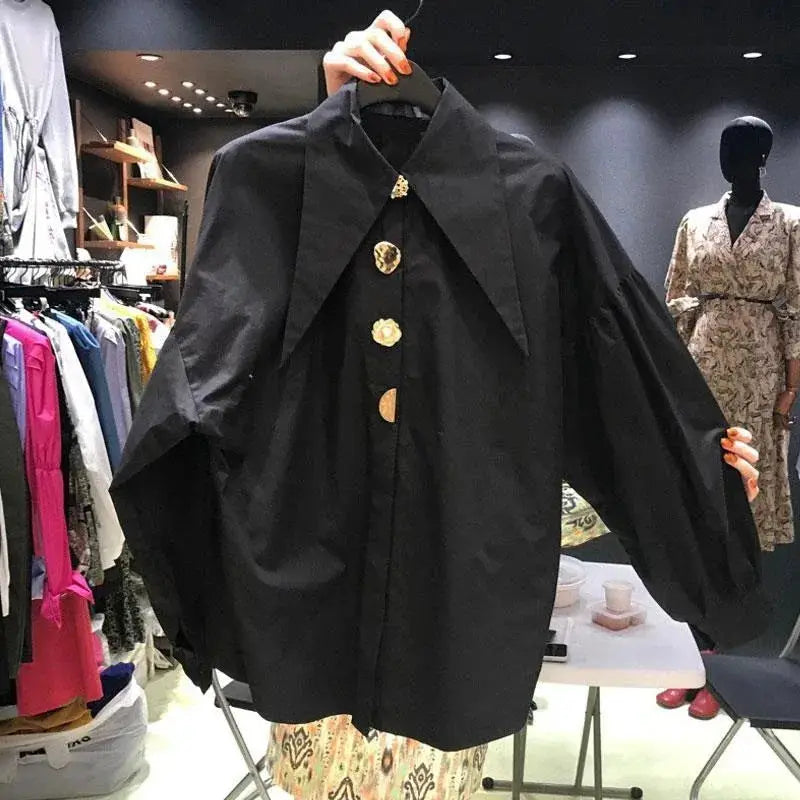 Black oversized blouse with wide cape sleeves and large decorative buttons