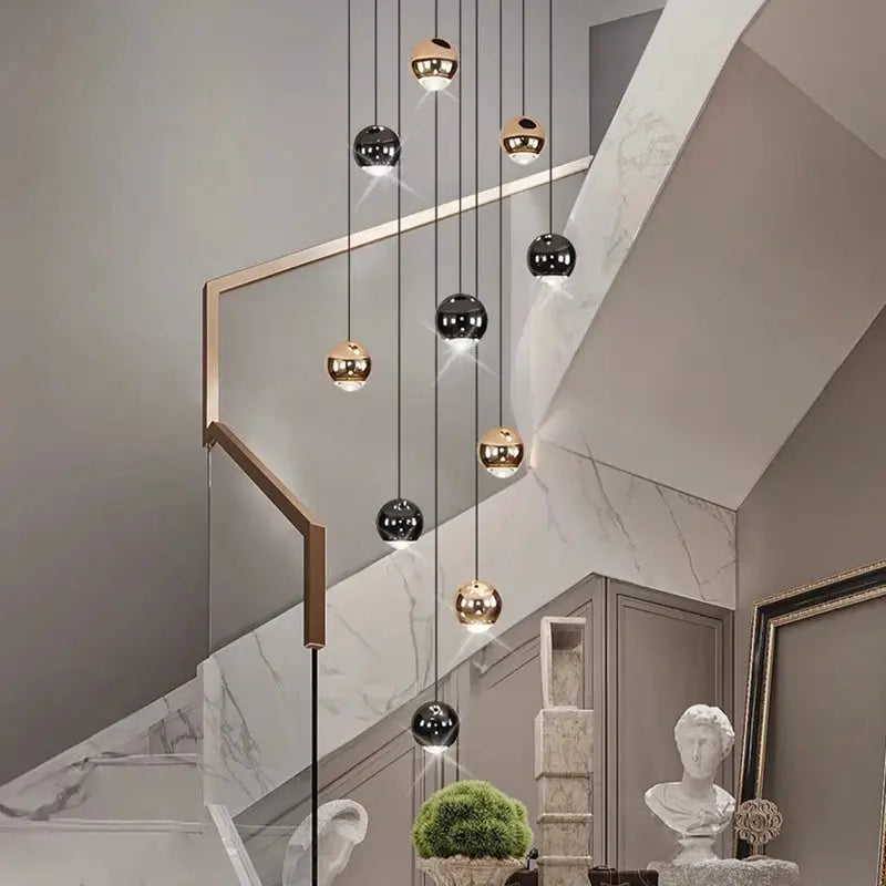 Pendant light chandelier by Simples Market; modern hanging LED spheres in black and gold over a staircase.