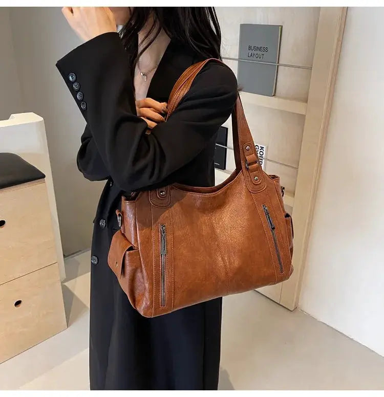 Soft interior compartment shoulder bag in brown PU leather with front zip pockets and twin handles