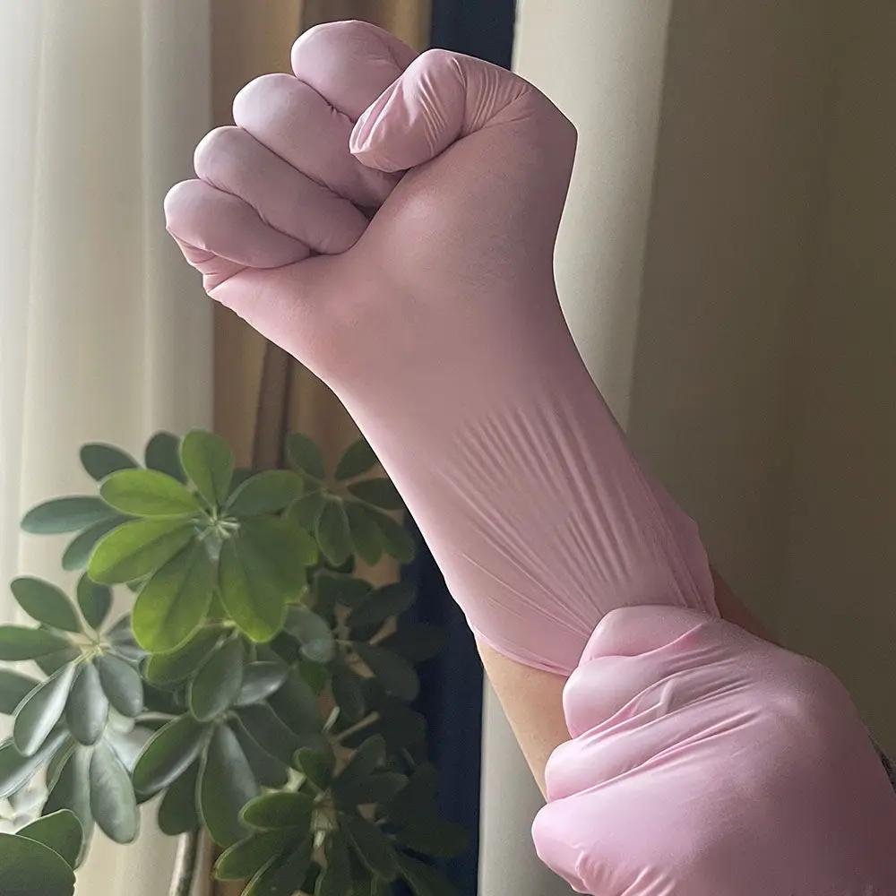 Disposable nitrile glove in light pink worn on hand for kitchen use