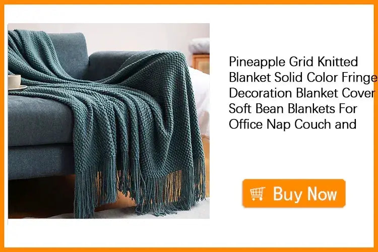 Teal knitted throw blanket with fringe draped over a gray sofa.