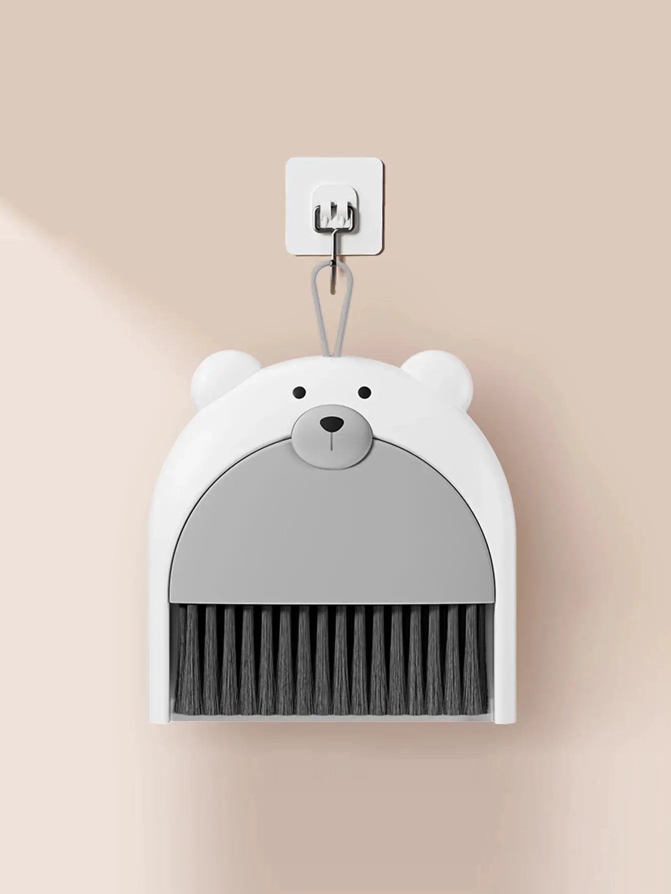 Bear-shaped broom and dustpan set by Simples Market with black bristles and white body, wall-hung.