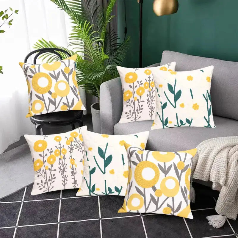 Simples Market six cotton throw pillows with boho floral patterns in yellow, gray and green, arranged on sofa and floor.