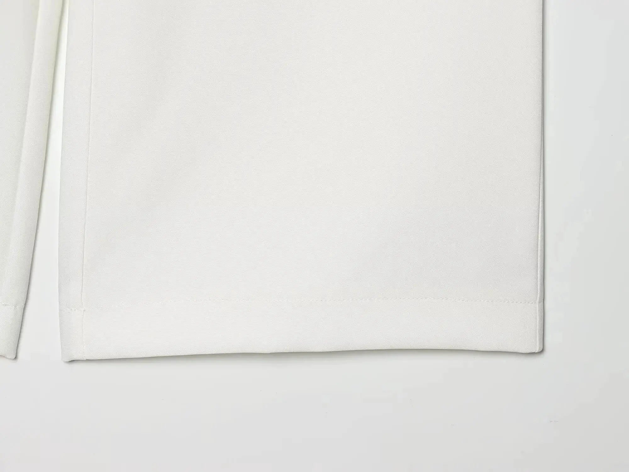 White blazer fabric close-up showing seam and folded edge