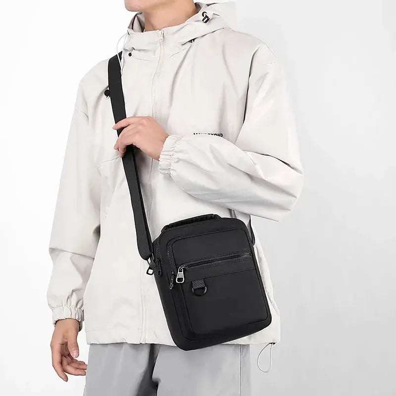 Messenger sling bag for men by Simples Market in black with front zipper pockets, worn crossbody