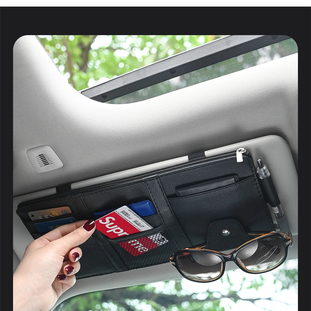 Black leather car sun visor organizer with card slots, pen holder, and sunglasses clip; Gucci sunglasses attached.