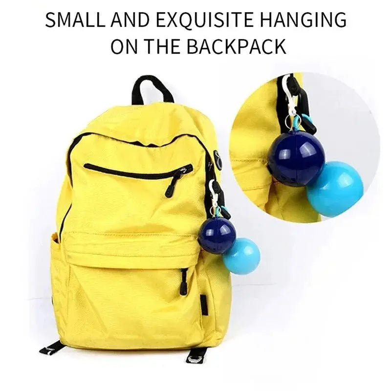 Yellow backpack with blue and sky-blue sphere keychain hanging from the zipper