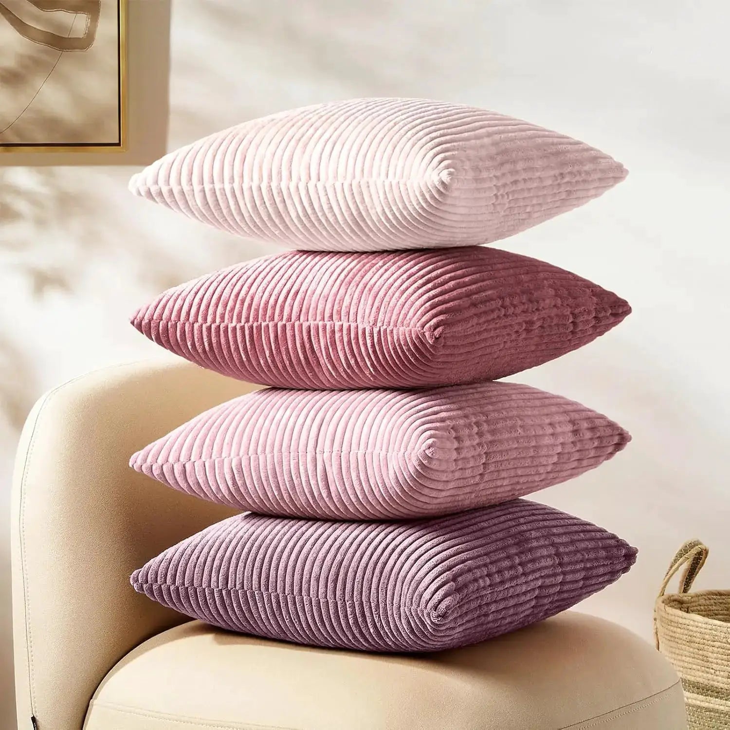 Four lilac-pink corduroy striped pillow covers stacked on a beige chair