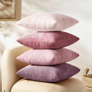 Four lilac-pink corduroy striped pillow covers stacked on a beige chair