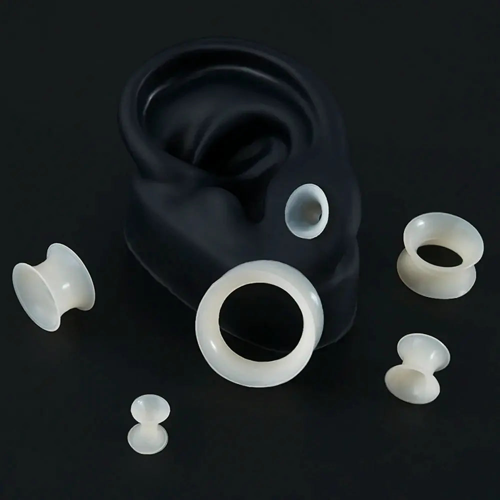 Six white silicone ear tunnels with double-flare ends; soft, skin-thin, flexible