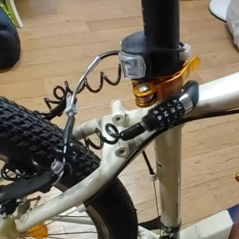 Simples Market 4-digit combination bike lock with coiled steel cable on a white bicycle frame