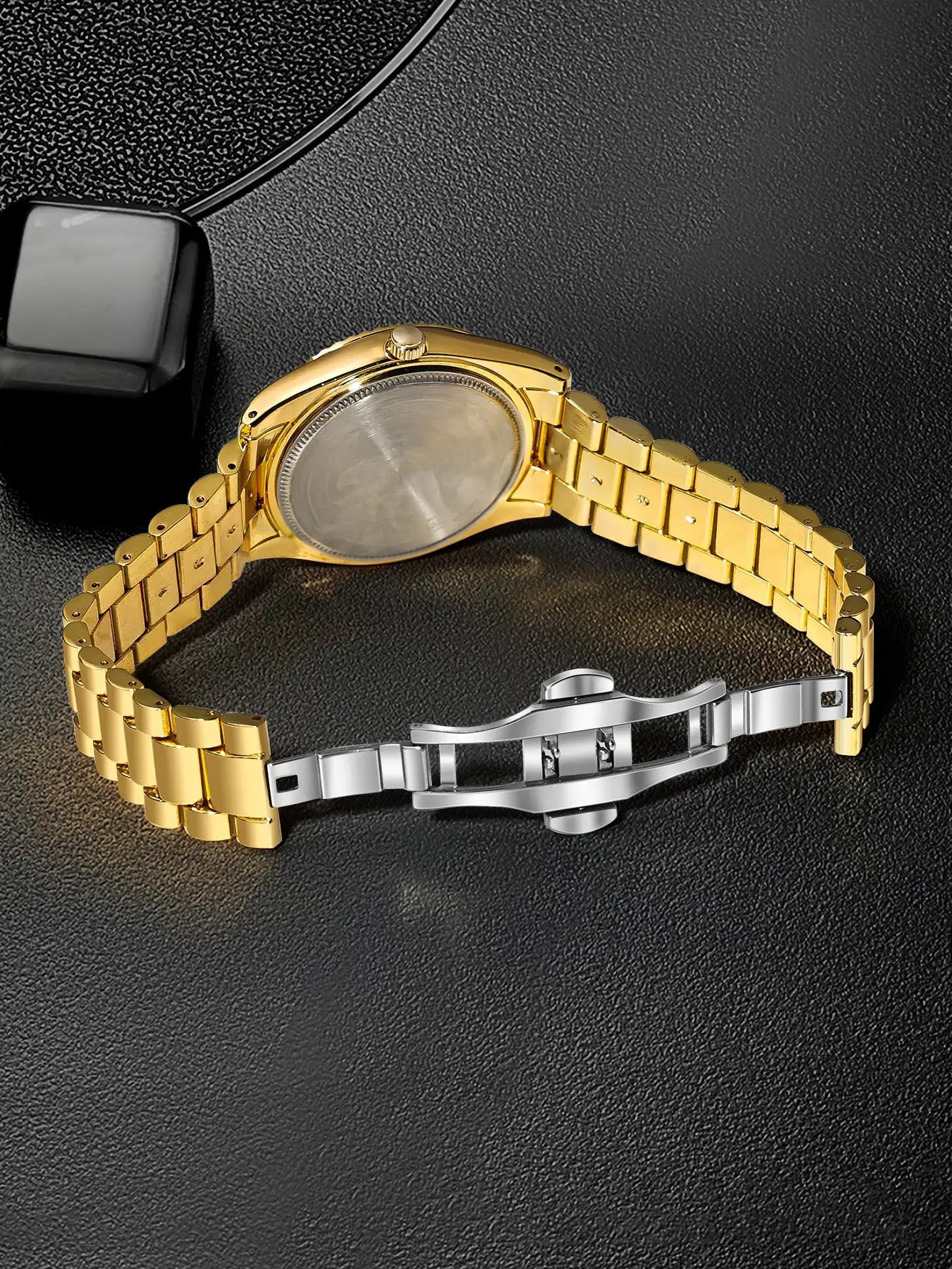 Gold-tone stainless steel men's watch with a linked bracelet and silver deployment clasp, back view