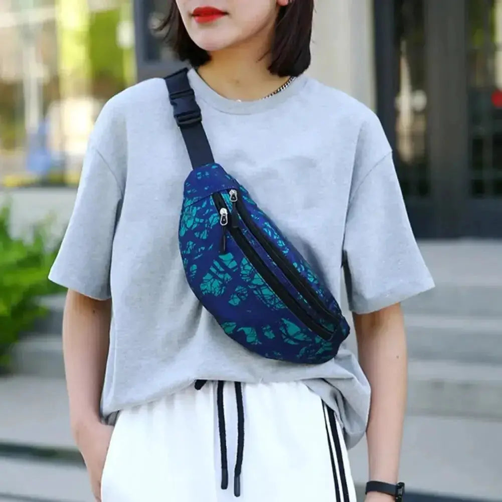 Sports waist pack in blue leaf-patterned fabric with a black adjustable strap worn crossbody.