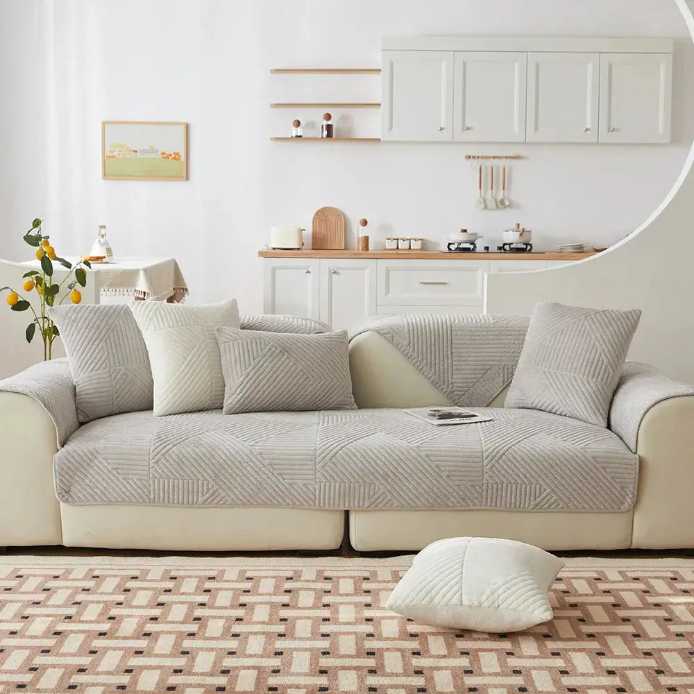 Crystal Velvet Sofa Cover by Simples Market on a beige sofa; gray velvet quilted, non-slip slipcover for living room.