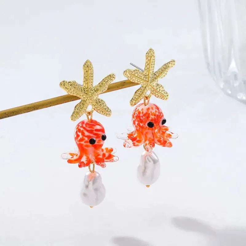 Cute octopus earrings with gold starfish tops, orange glass octopuses and white pearl drops