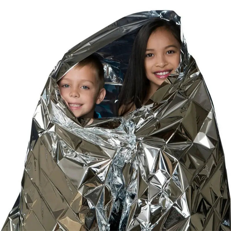 Simples Market emergent Mylar thermal blanket; silver space blanket wrapped around two kids.