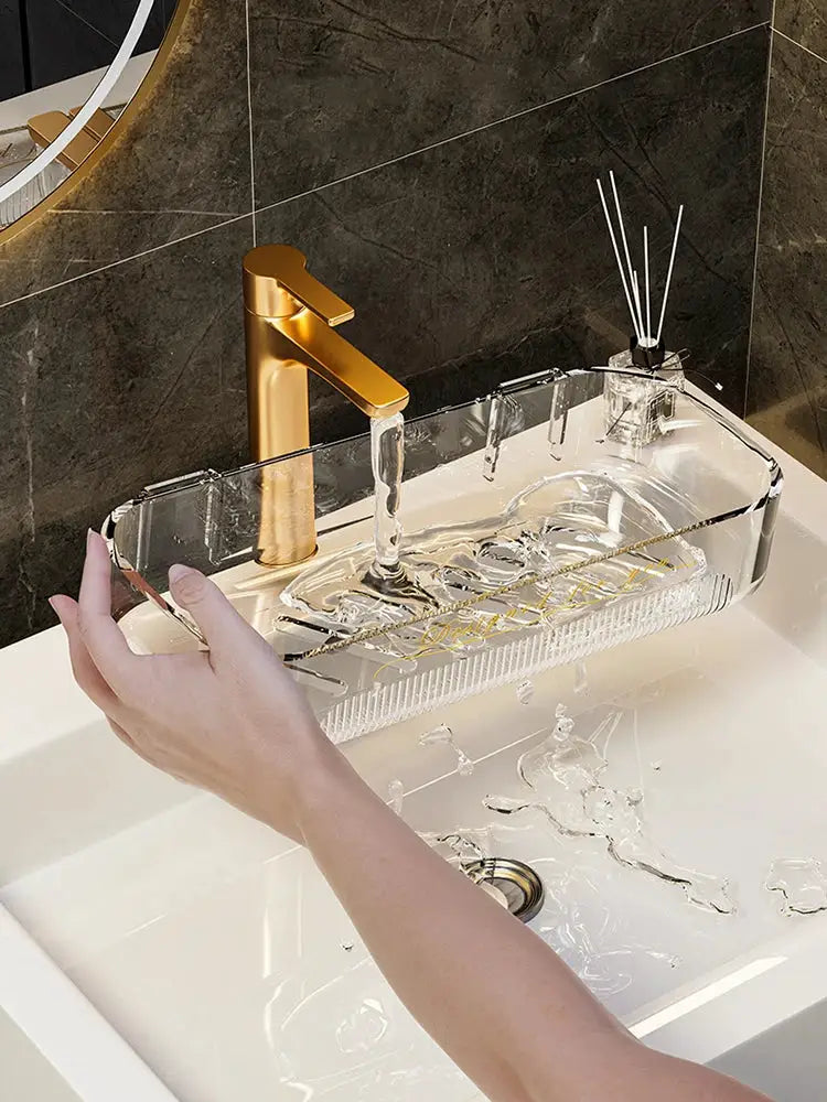 Clear acrylic bathroom storage rack on sink with gold faucet, holding toiletries