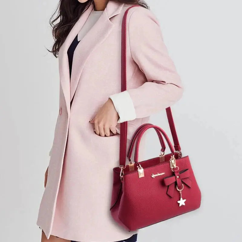 Red crossbody handbag by Simples Market with top handles and bow charm